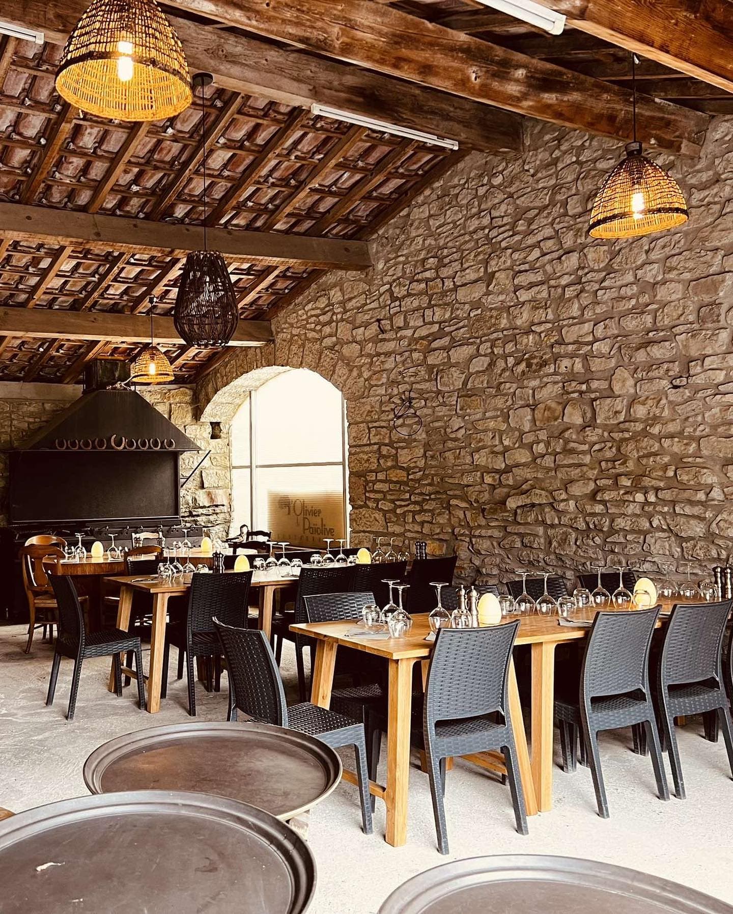 La salle voûtée en pierre avec ses poutres apparentes et sa grande cheminée