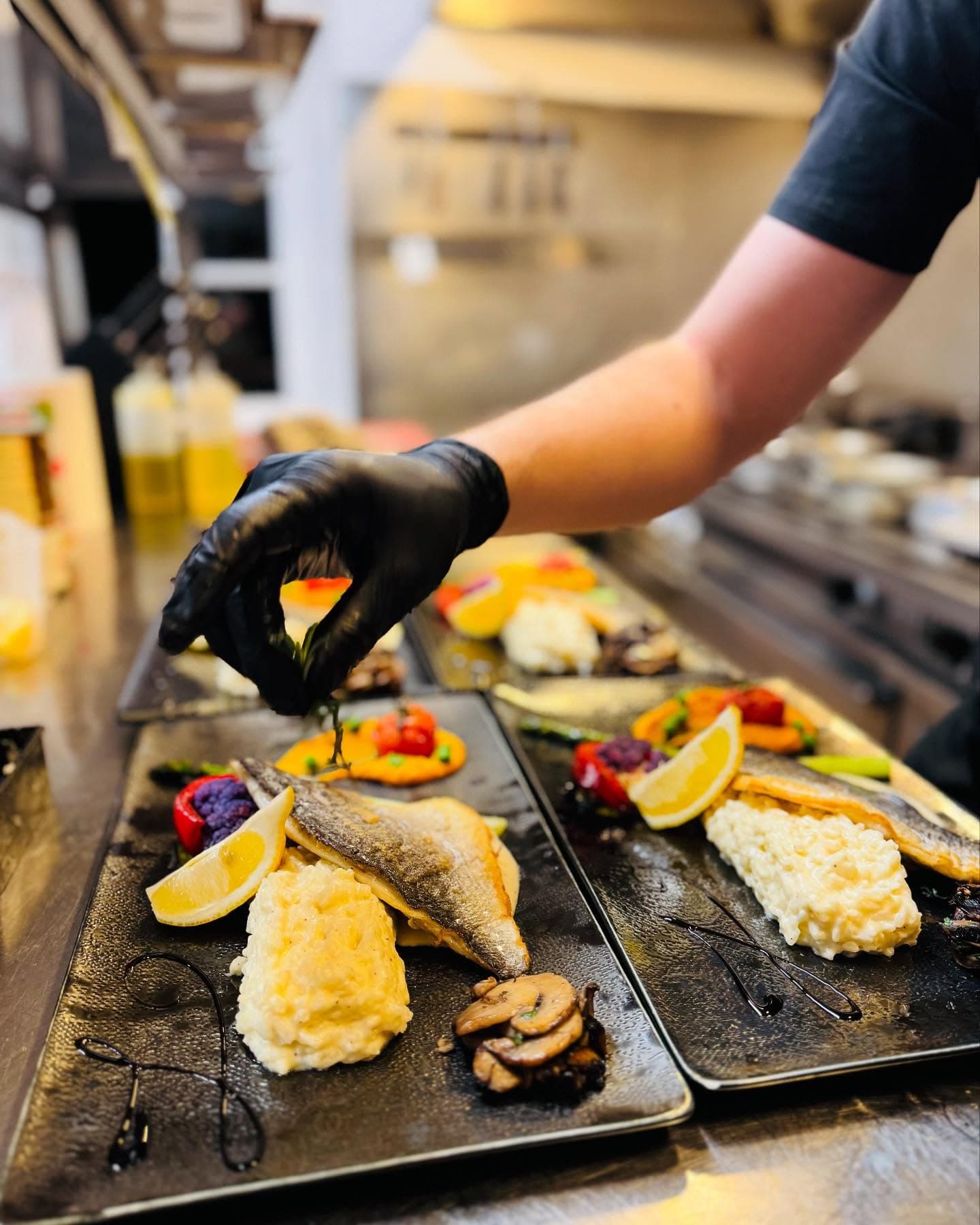 Le chef dressant une truite avec polenta crémeuse et légumes du marché